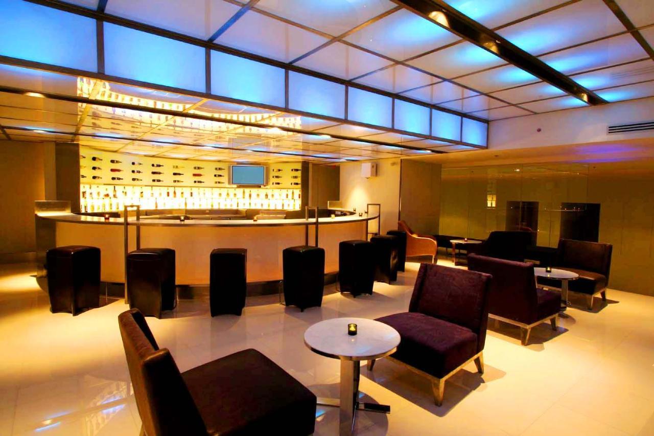 Pathumwan Princess Hotel - Sha Extra Plus Certified Bangkok Exterior photo The photo shows a stylish and modern lounge or bar area. It features a contemporary bar design with a backlit display of bottles. The seating arrangement includes black and purple upholstered chairs and stools arranged around small tables. The lighti